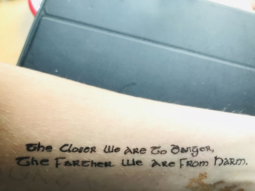 J. R. R. Tolkien inspired tattoo with a handwritten quote on a forearm.