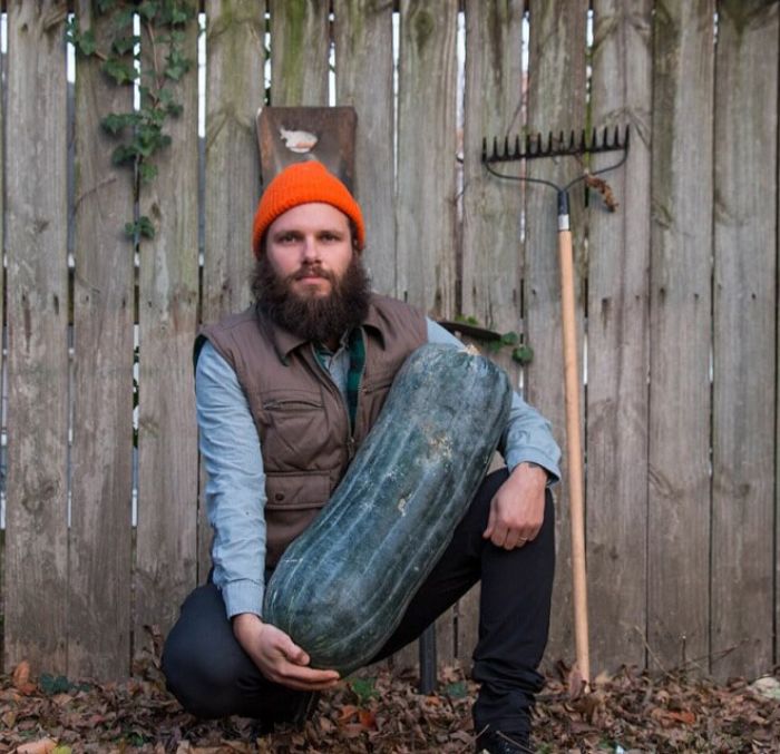 Bearded man wearing an orange beanie holding a large vegetable, illustrating funny vegan hunters humor outdoors.