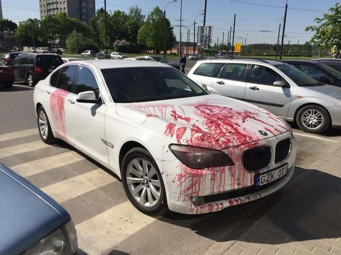 White BMW car sprinkled with red paint 