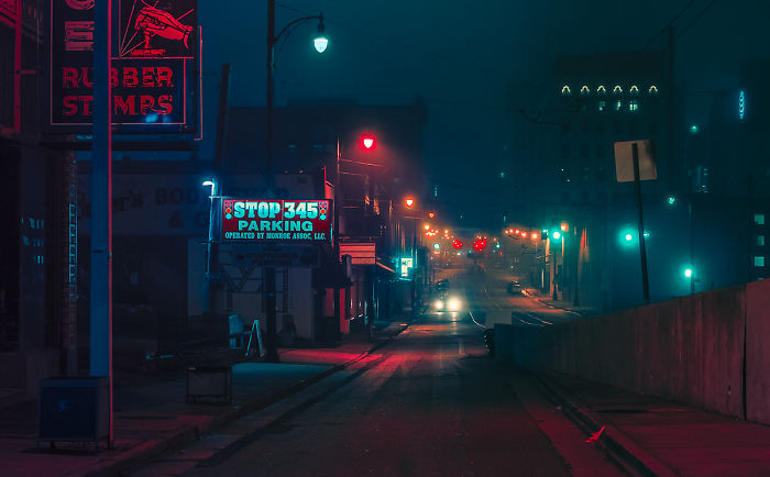 Empty dimly lit street at night in one of the most dangerous cities in America, with neon signs and traffic lights glowing.