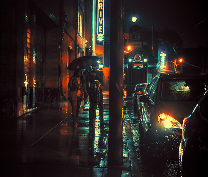 Couple walking under umbrella on wet street at night in one of the most dangerous cities in America.