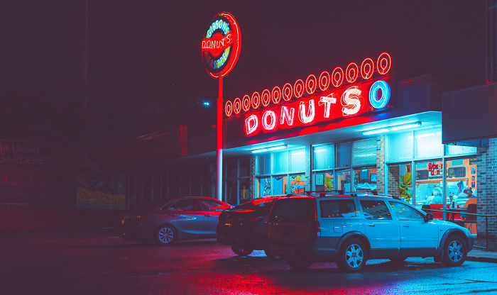 Neon-lit donut shop at night with cars parked outside, capturing a scene from one of the most dangerous cities in America.