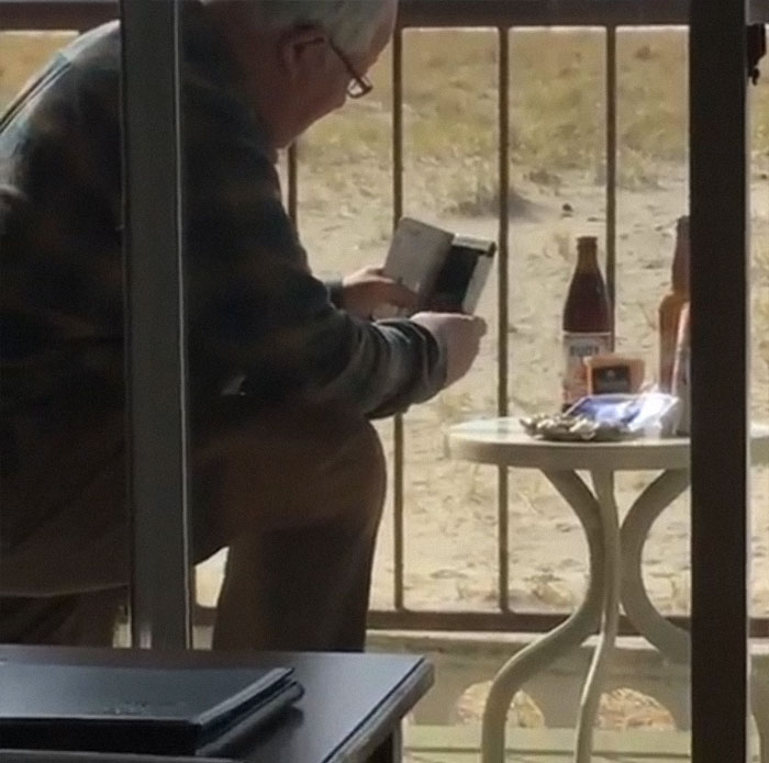 Old man taking a picture of beer and cigarettes on a table 