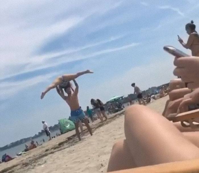 Woman taking a picture of a man holding his wife above his head 