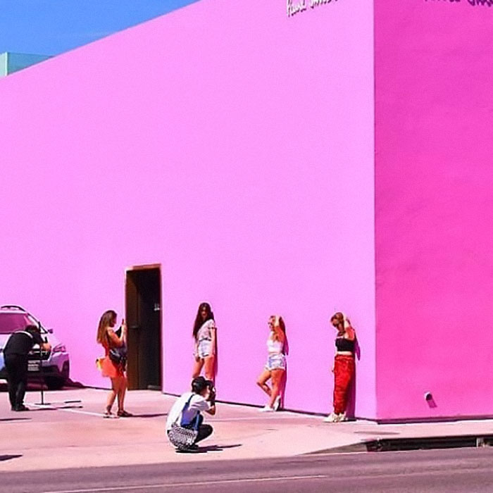 Multiple girls posing in front of fully pink colored wall 