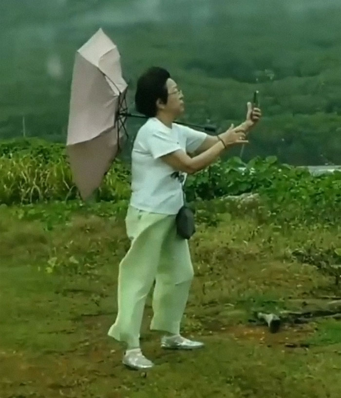 Man taking a selfie while his umbrella is breaking 