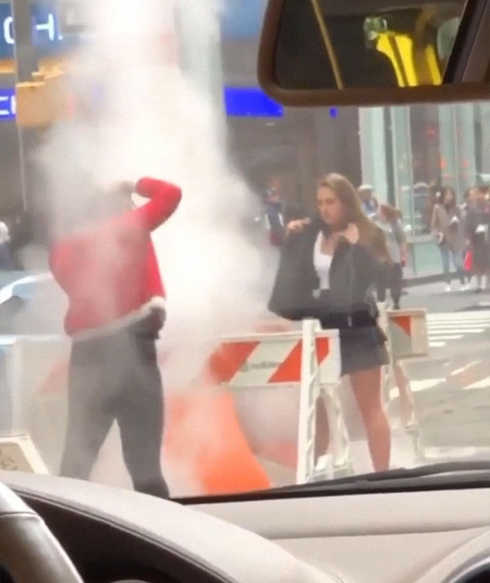 Man taking a picture next to a fire in the street 