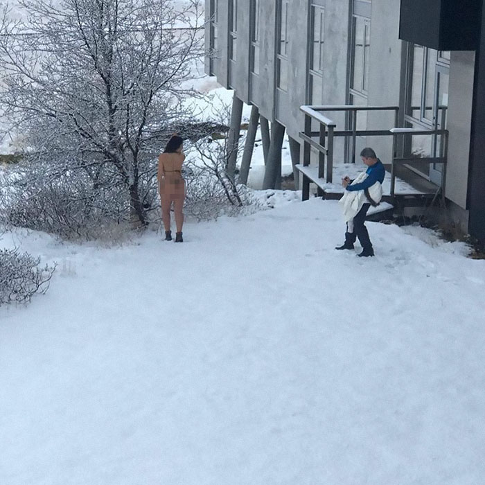 Man taking a picture of a semi n**e woman in the snow 