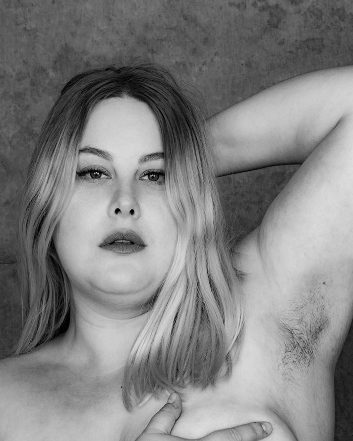 Woman showing natural armpit hair in a black and white portrait promoting body positivity for JanuHairy campaign.