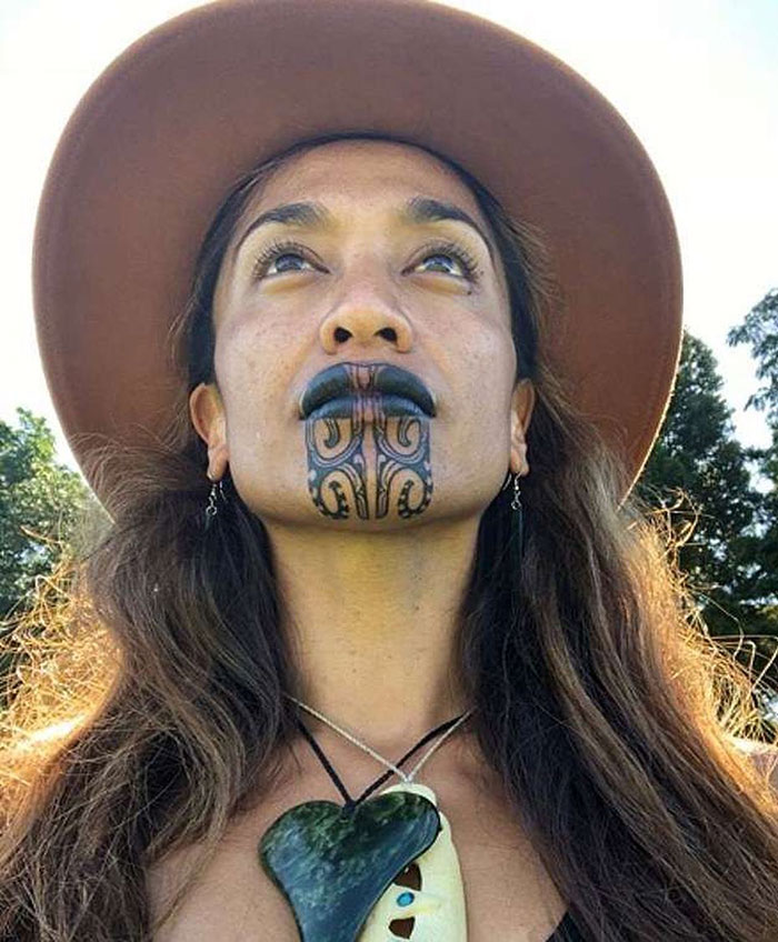 Woman with face tattoo, wearing a hat and necklace, emphasizes respect for cultural tattoos. Woman with face tattoo, wearing a hat and necklace, emphasizes respect for cultural tattoos.
