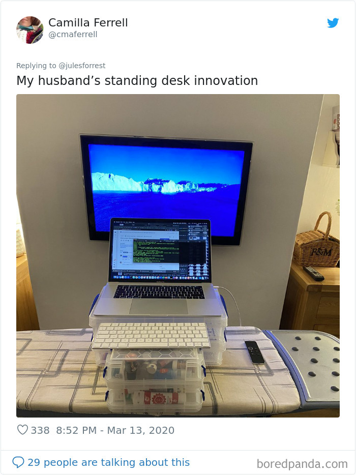 Improvised standing desk setup on an ironing board with stacked storage boxes showing reality of working from home.