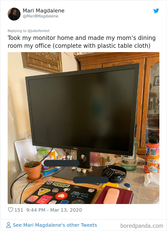 Home workspace reality showing a cluttered dining room desk with monitor, laptop, headphones, and personal items for working from home.