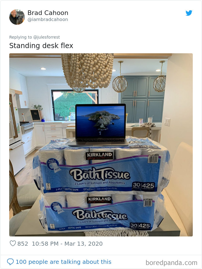 Improvised standing desk setup using stacked toilet paper packs for remote work at home workspace.