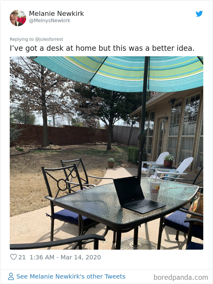 Outdoor work from home setup with laptop on glass table under large umbrella, showing reality of remote workspace setups.