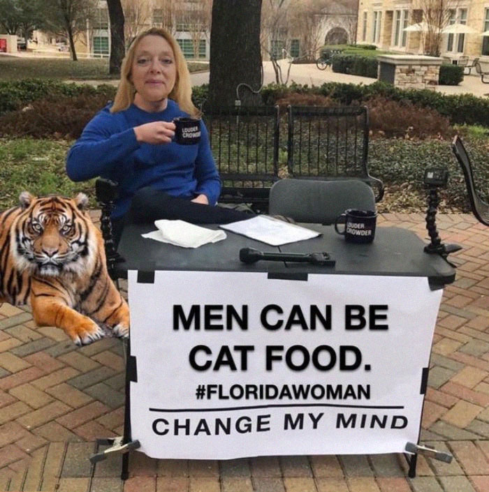 Woman with tiger and "Men can be cat food" meme sign at a park, inspired by Tiger King.