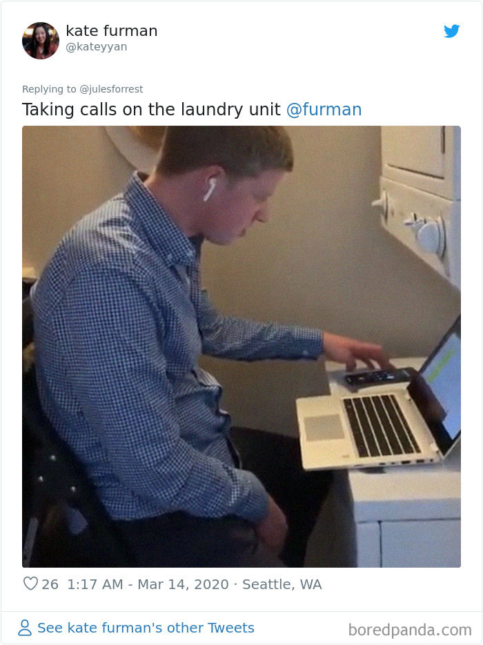 Man working from home, taking calls at a laundry unit with laptop and earbuds in an unconventional workspace setup.