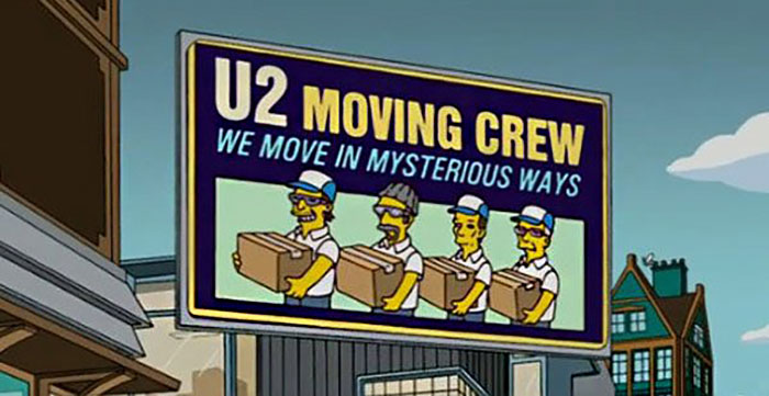 Billboard in The Simpsons featuring a witty sign for U2 Moving Crew with the phrase we move in mysterious ways.