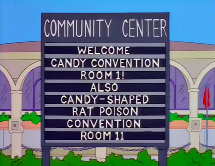 Community center sign from The Simpsons with witty messages about candy convention and candy-shaped rat poison.