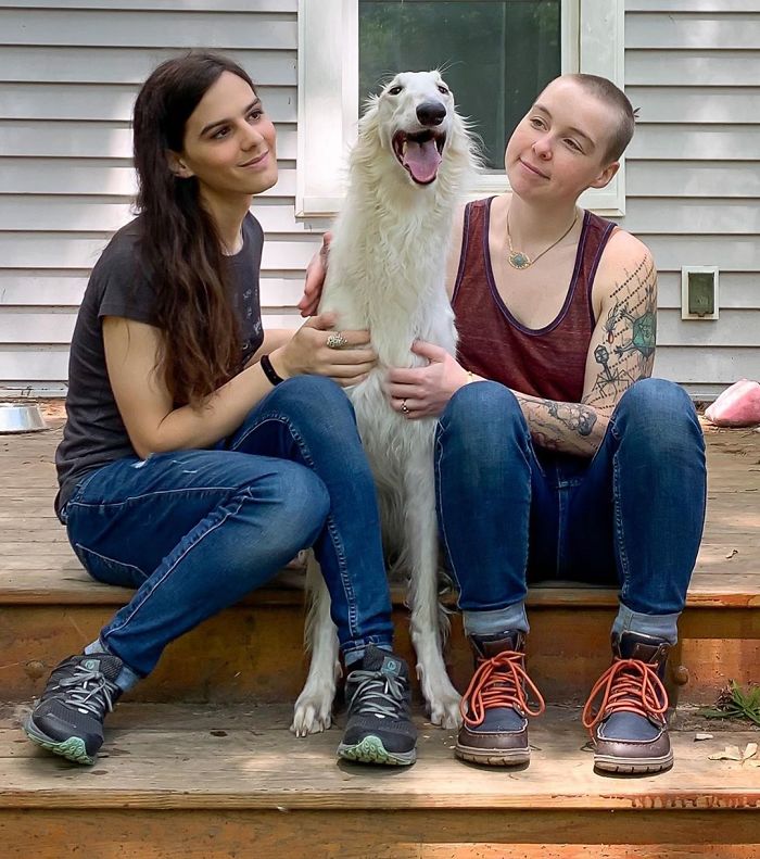 Very long dog with a 12.2-inch snout sitting between two people on wooden steps. Very long dog with a 12.2-inch snout sitting between two people on wooden steps.