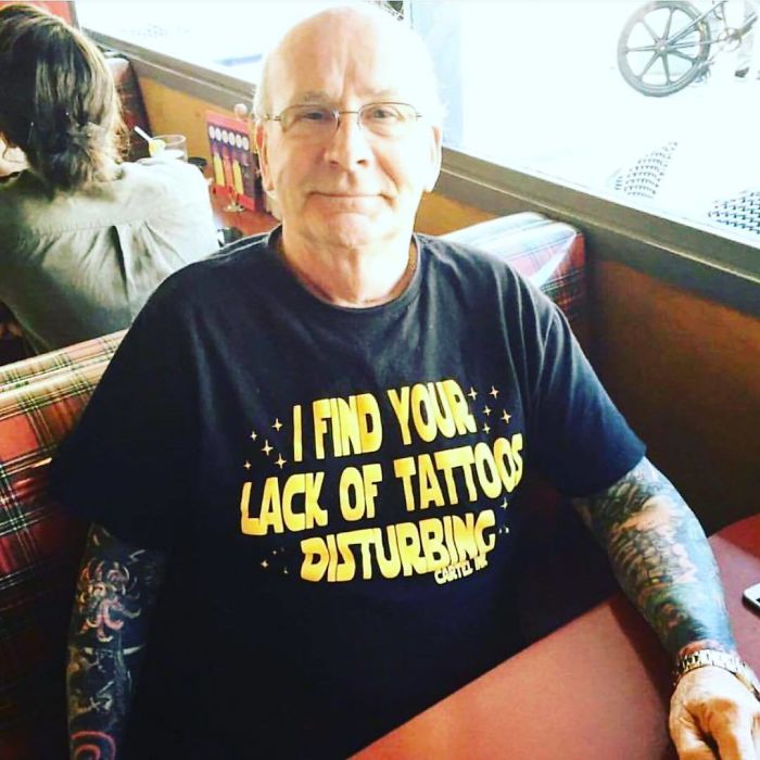 Senior with sleeve tattoos wearing a shirt that says, "I find your lack of tattoos disturbing," proving tattoos look awesome.
