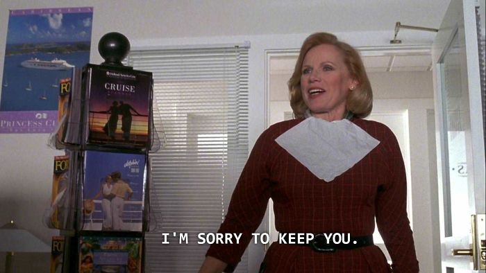 In The Truman Show, The Travel Agent Kept Truman Waiting Because She Has Never Needed To Show Up For Work Before. Also She Is Still Wearing Her Makeup Bib Since It Was A Rush Job