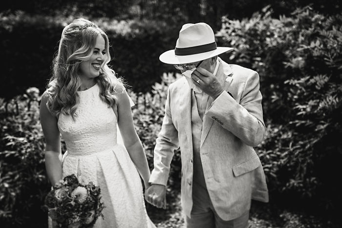 Bride and father sharing an unstaged joyful moment holding hands during a candid wedding photo outdoors.