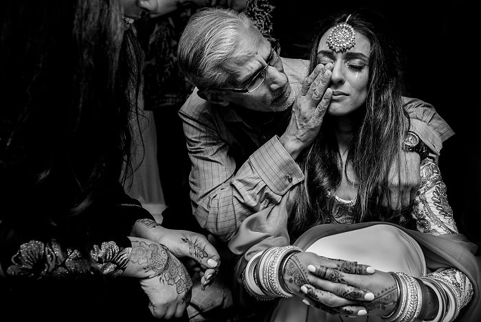 Unstaged father-daughter moment at a wedding showing emotional bonding and traditional attire in black and white photography.