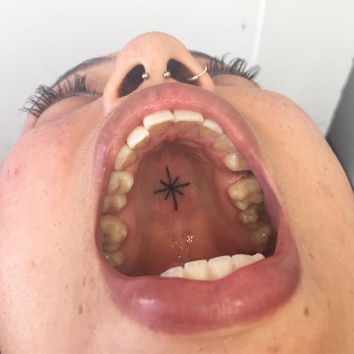 Tattoo on the roof of an open mouth, showcasing unconventional body art placement.