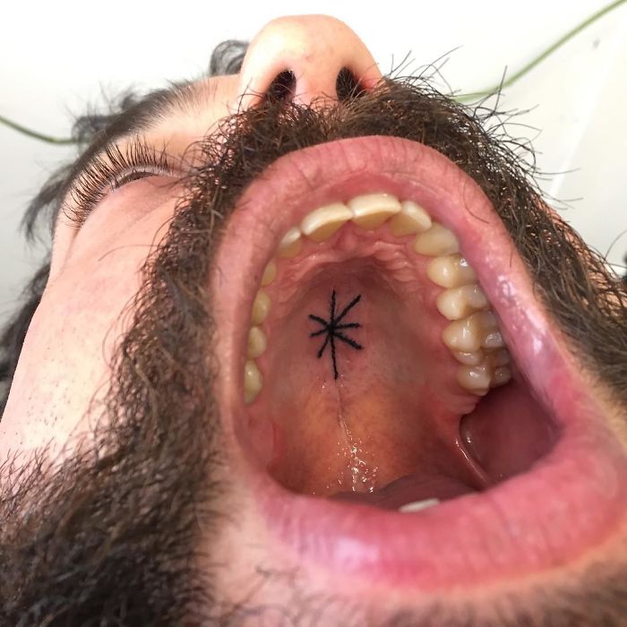Tattoo in the shape of an asterisk on the roof of a person's mouth, showcasing unconventional body art.