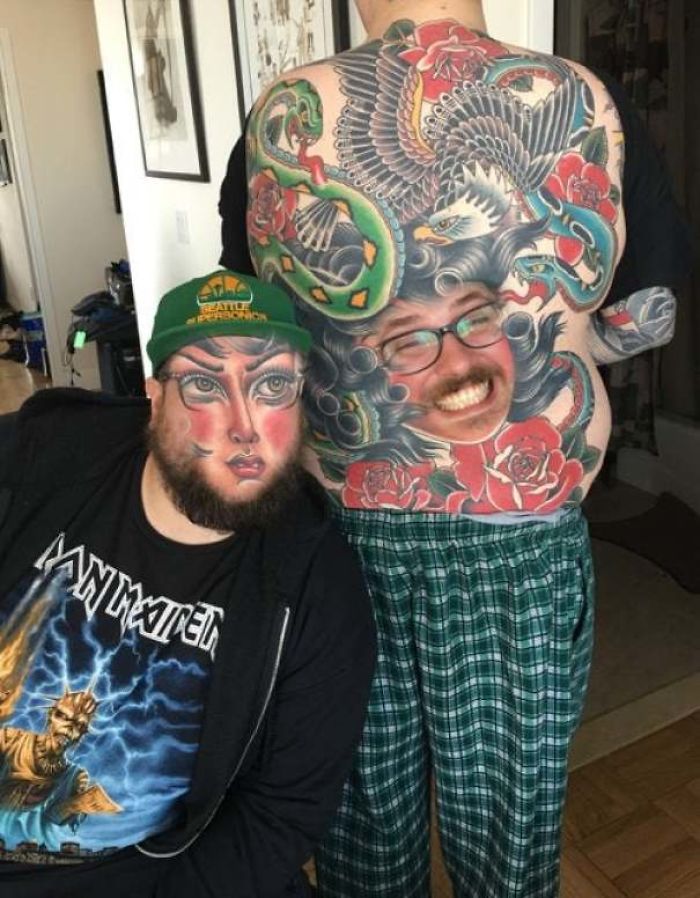 Face swapping tattoos on two people, one with a colorful full back tattoo, in a room with art on the walls.