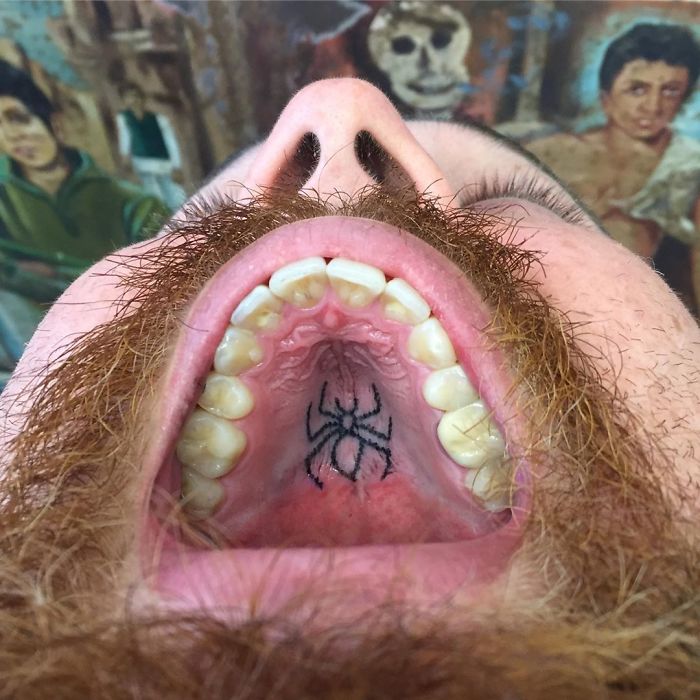 Tattoo on the roof of the mouth showing a spider design in close-up view.