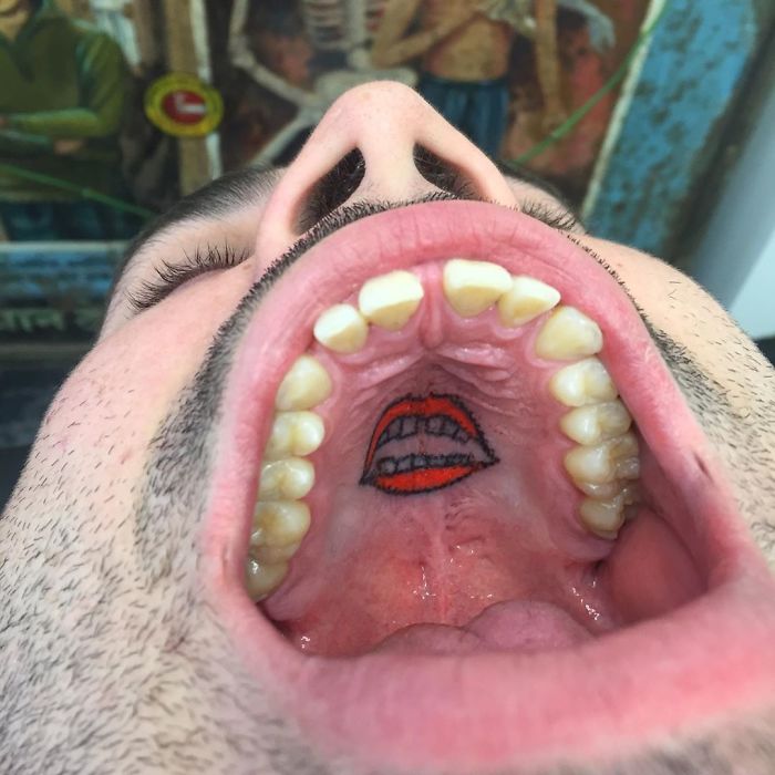 Unconventional tattoo on the roof of the mouth depicting red lips and teeth, showcasing artistic creativity.