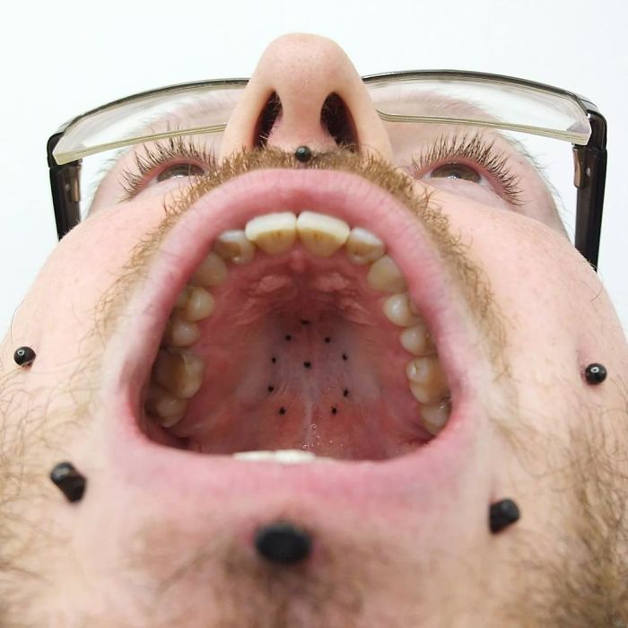 Tattoo on unconventional body part: roof of mouth, small black dots visible inside.