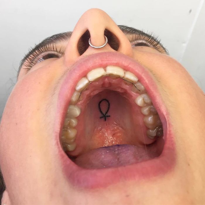 Tattoo on the roof of a mouth, featuring a small symbol, showcasing unconventional body art canvas.