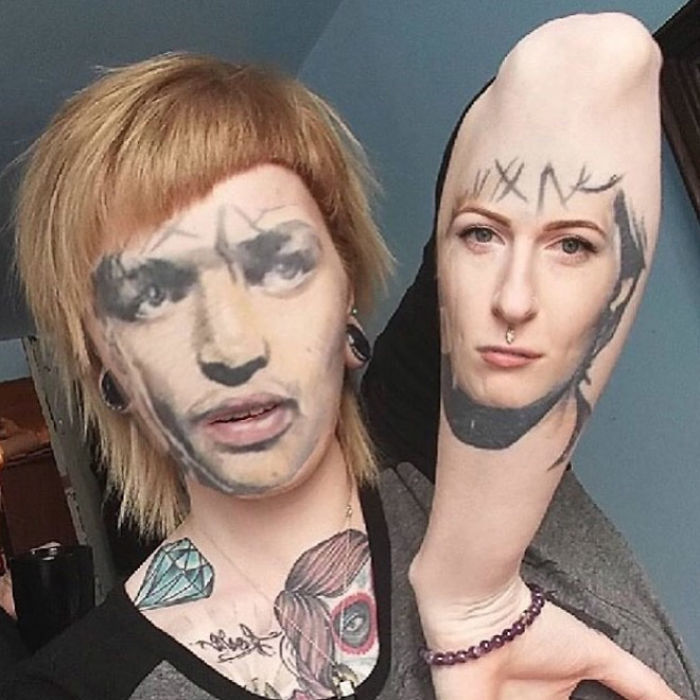 Person with face swap tattoos, featuring a face tattoo on an arm and a different visage on their own face.