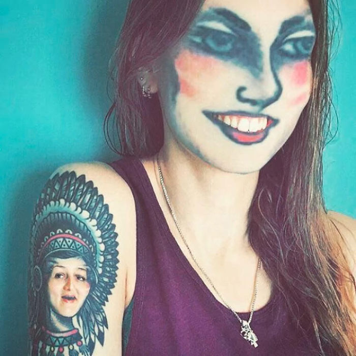 Face swapping tattoos create an unusual look on a woman with a tattooed arm against a blue background.