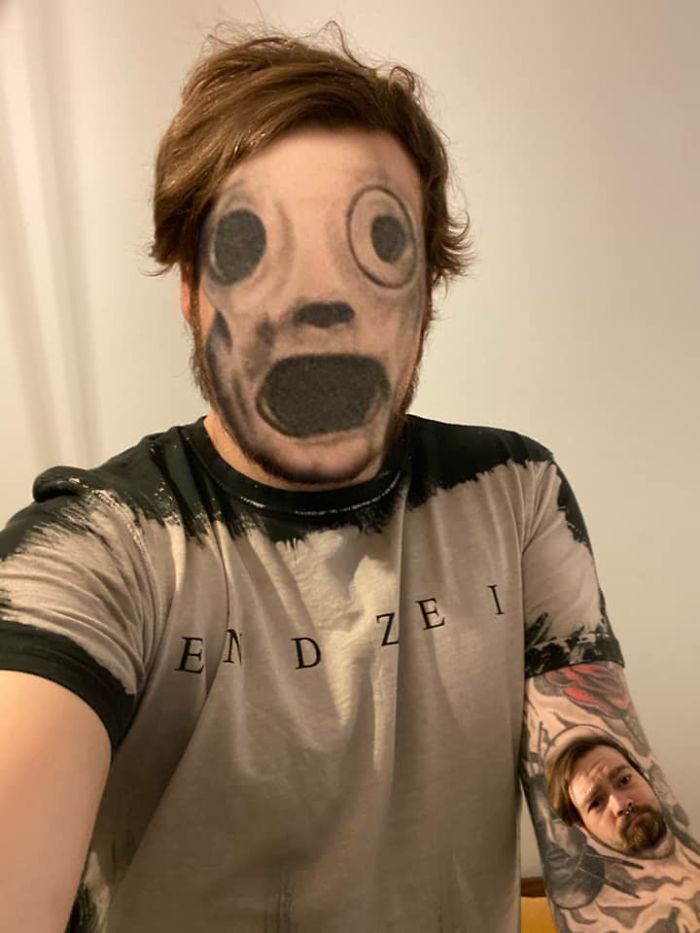 Face swap tattoo on a man's body, featuring an unsettling, exaggerated face design on his real face and arm.