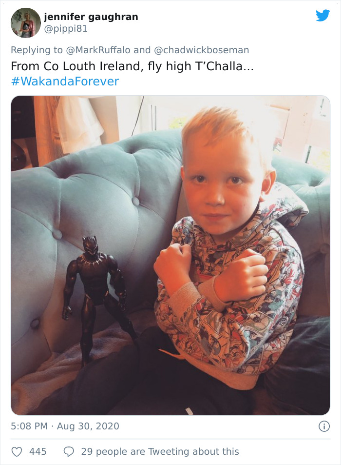 Child sitting on couch making Black Panther salute next to action figure honoring late Black Panther memorials.