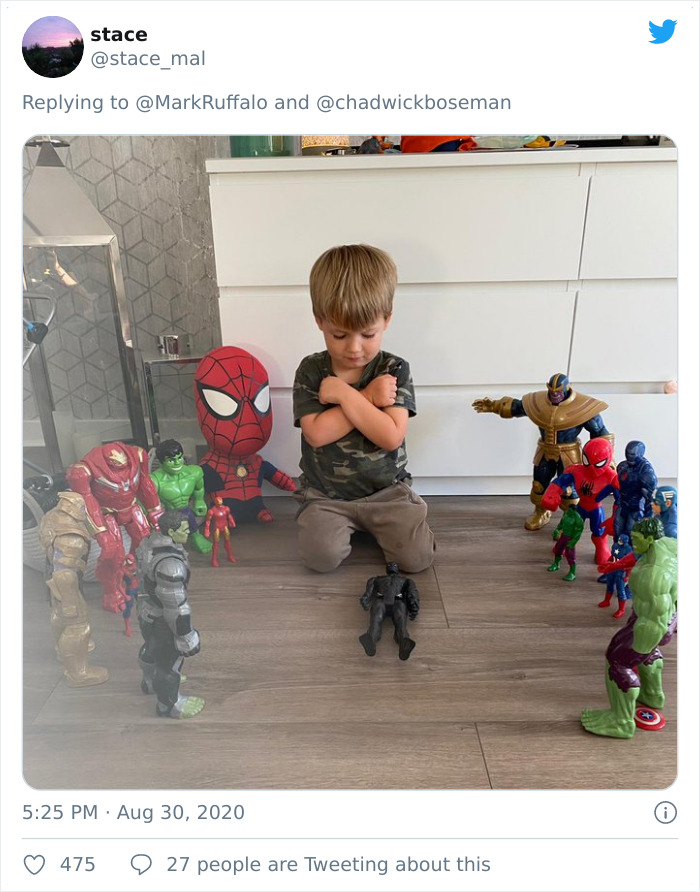 Young boy honoring late Black Panther with action figure memorial surrounded by Marvel superhero toys on floor.