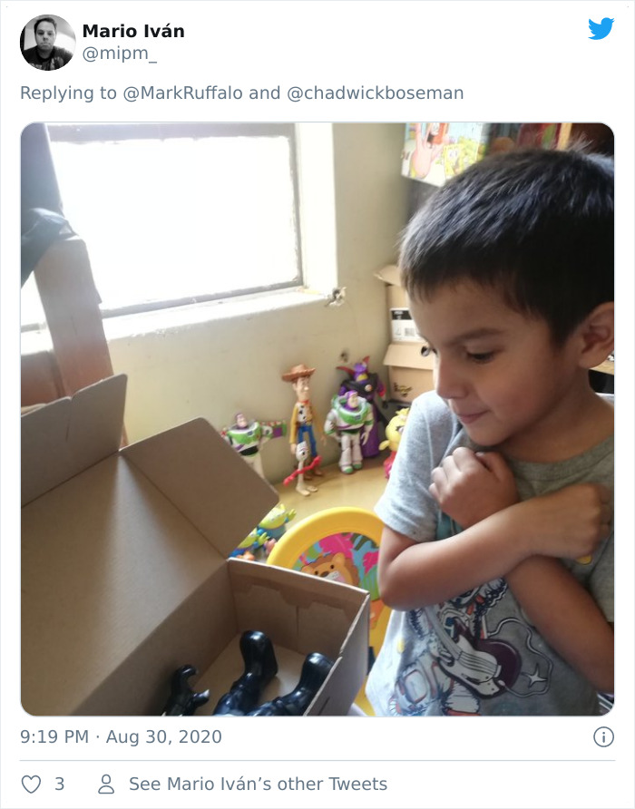 Young boy crossing arms in Black Panther salute while looking at action figure memorial in a room with toys.