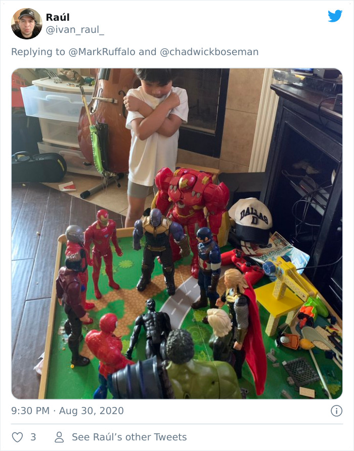 Child standing with arms crossed in a Black Panther action figure memorial surrounded by Marvel superhero toys.