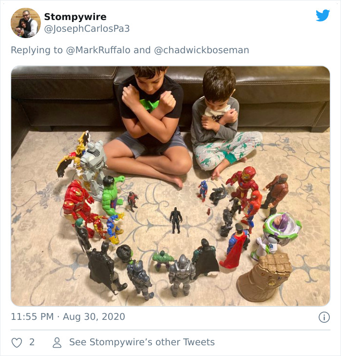 Two kids sitting on a carpet with Black Panther and superhero action figures honoring the late Black Panther.