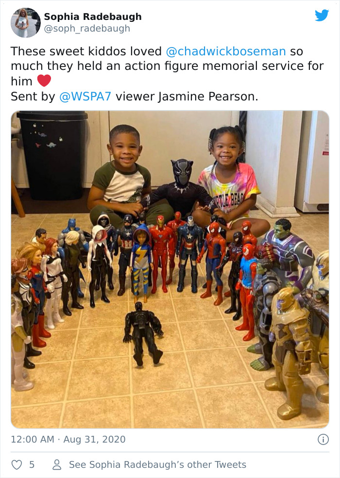 Two kids honoring late Black Panther with action figure memorial surrounded by superhero toys on a tiled floor.