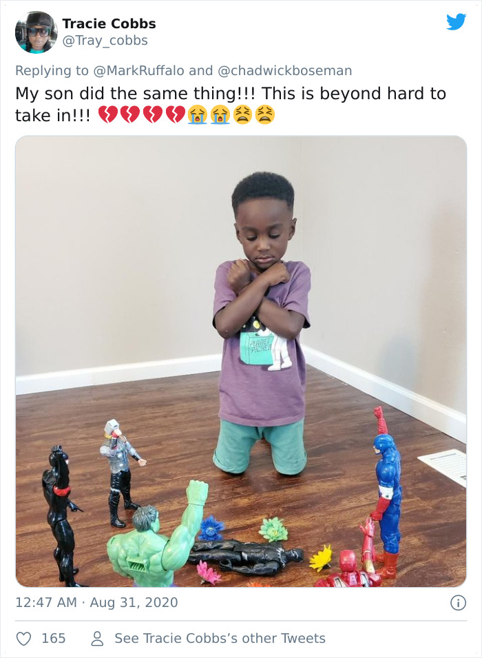 Young boy kneeling on floor with Black Panther and superhero action figures in an emotional kids honoring Black Panther moment.