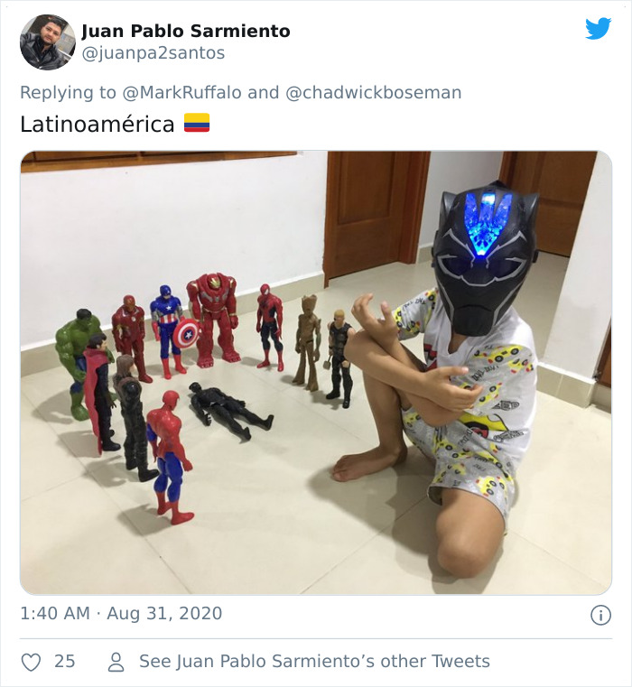 Child wearing Black Panther mask with action figure memorials honoring late Black Panther character on floor.