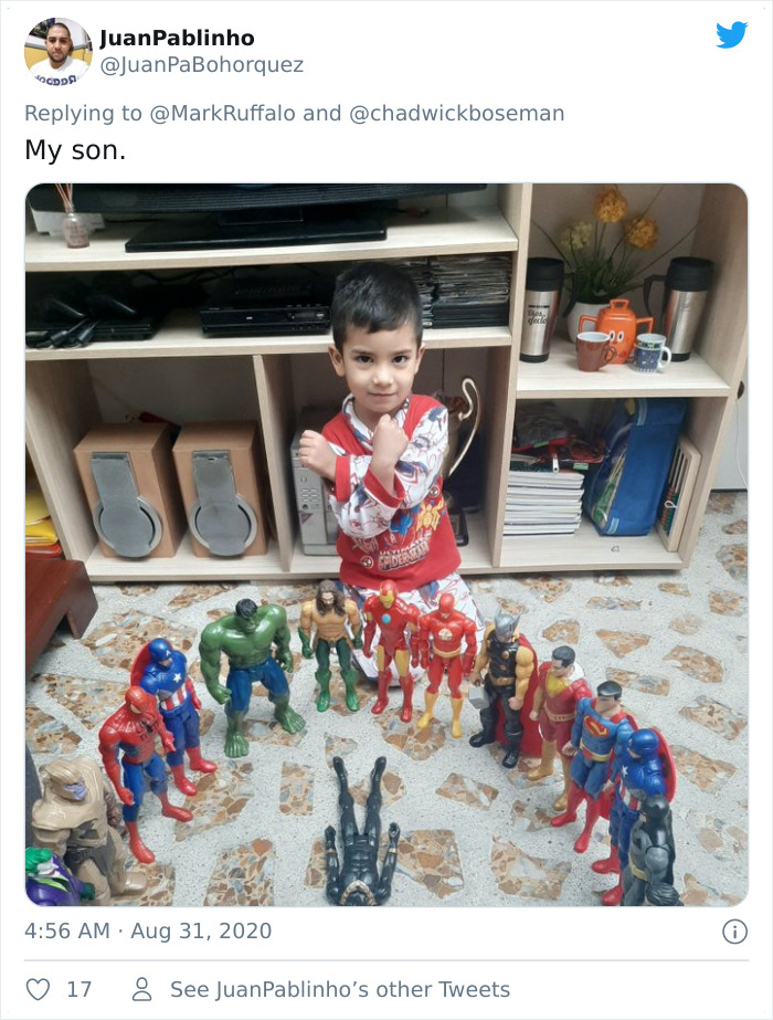 Young boy honoring late Black Panther with action figure memorials arranged in a circle on a tiled floor.
