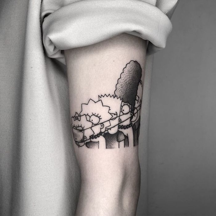 Covid-19 tattoo featuring cartoon characters wearing masks, creatively inked on an arm.