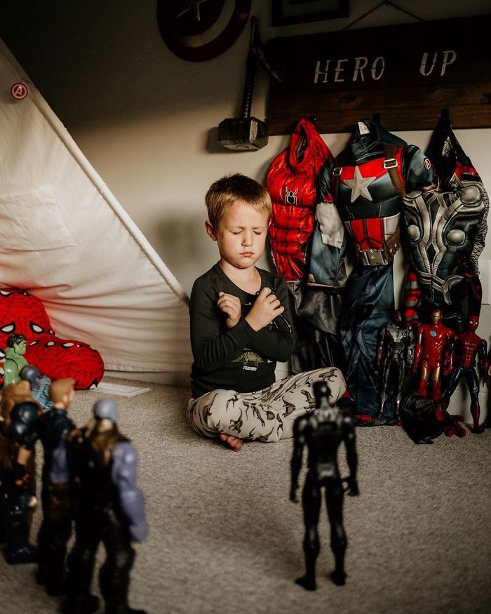 Young child sitting with eyes closed among Black Panther action figure memorials honoring late hero.