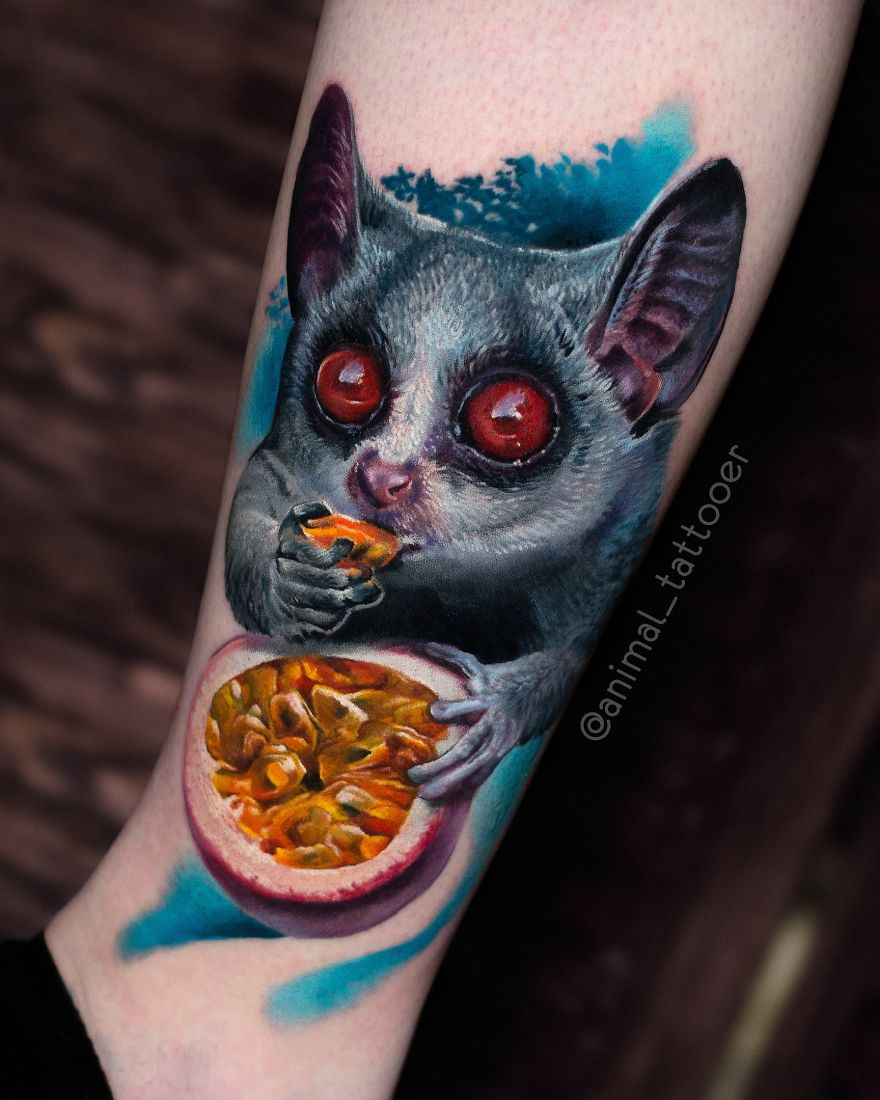 Colorful and bright animal tattoo of a tarsier holding fruit on a person's arm.