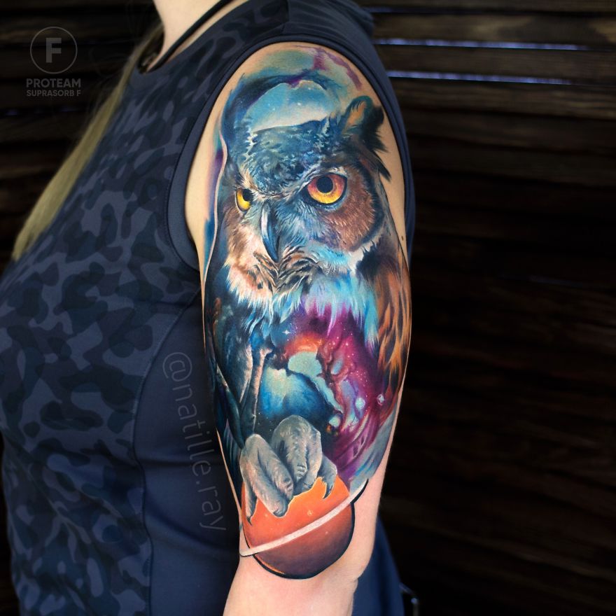 Colorful and bright owl tattoo on a person's arm, featuring vivid blues and oranges.